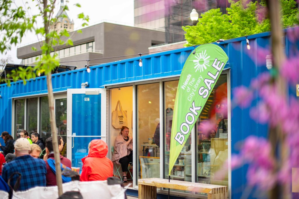 People visiting the book sale inside a shipping container at the Green Loop.