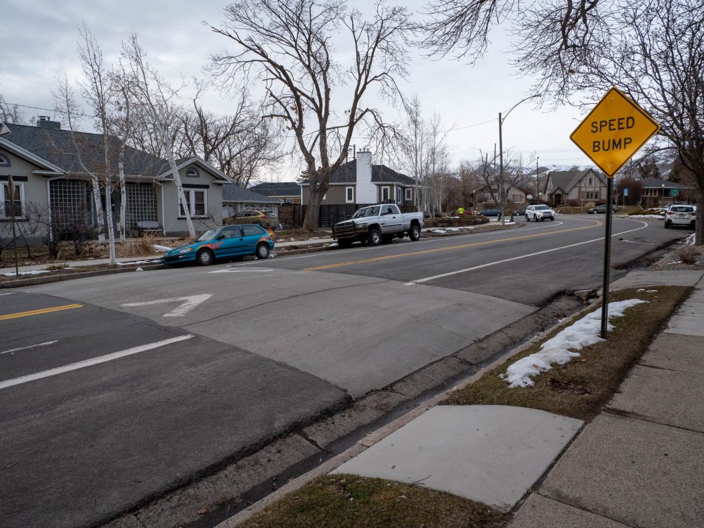A picture of a concrete speed hump on 1500 East with a sign that reads "Speed bump."