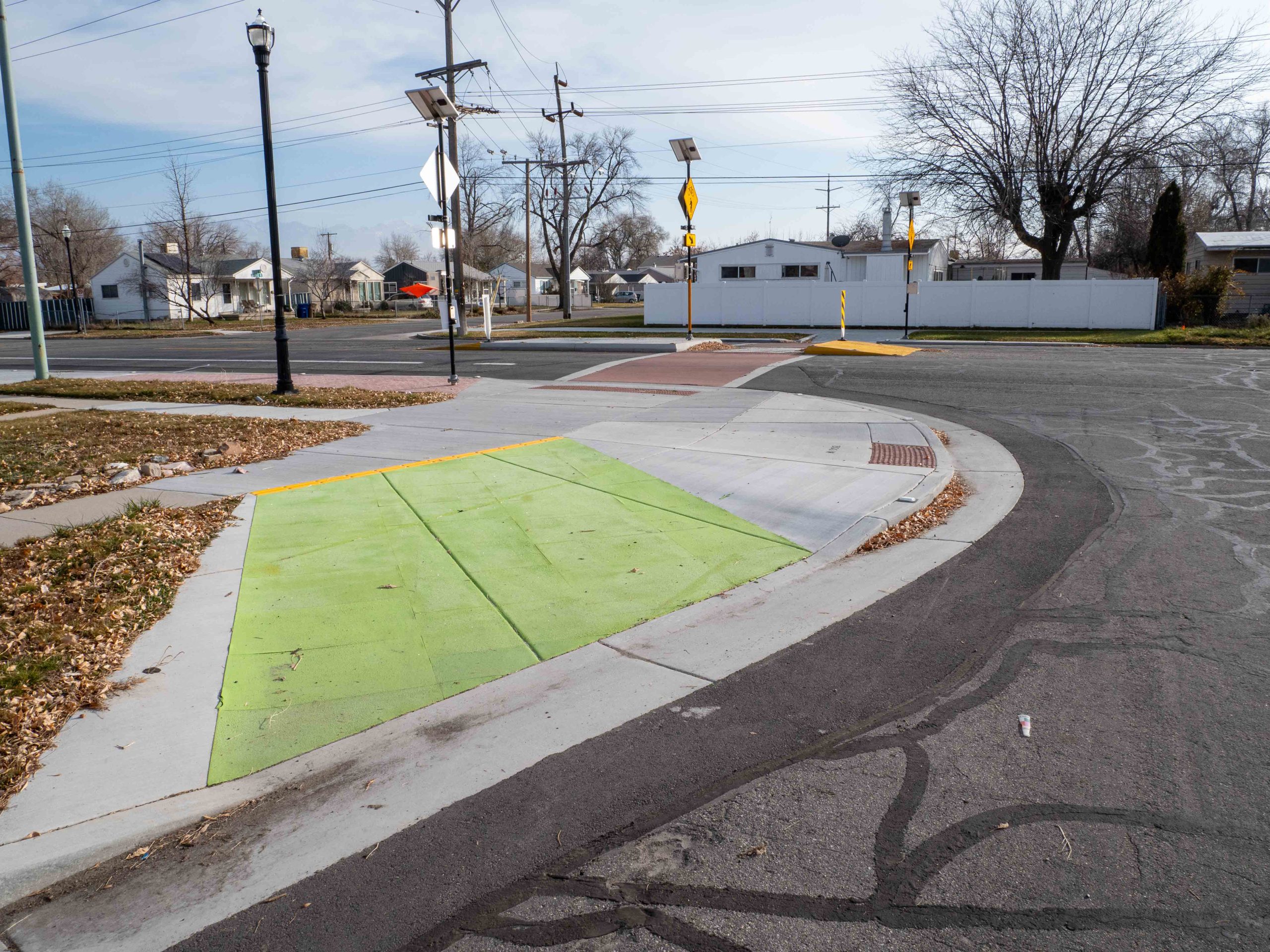 A picture of the crosswalk safety improvement at 1000 North and 1300 West. It includes upgraded ramps for people biking, a pedestrian refuge island, and flashing crosswalk signs.
