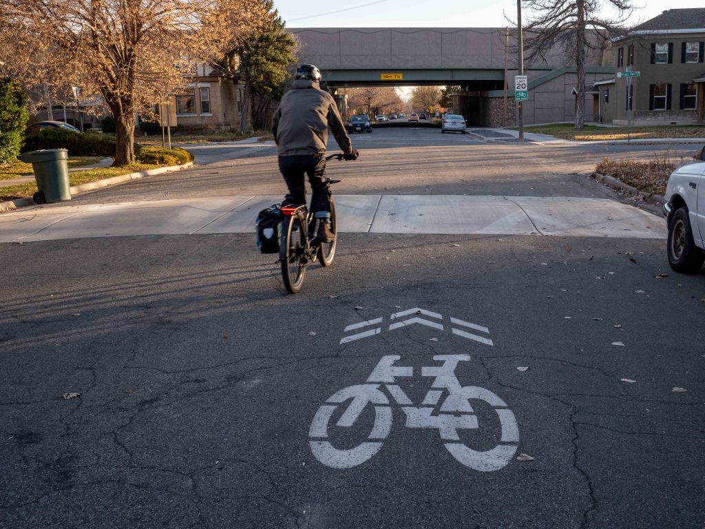 A photo of a person on a bicycle riding through a speed cushion on 600 East.