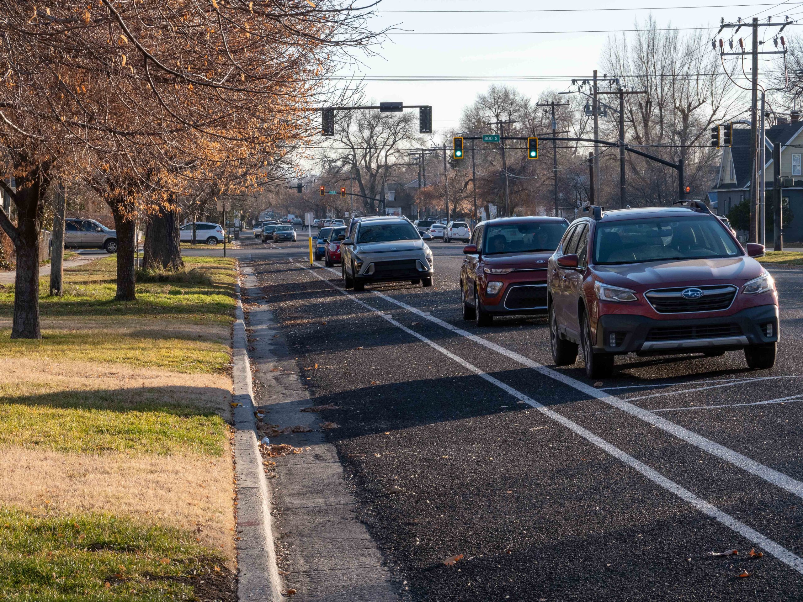 A picture of parking protected bike lanes on 400 East. The bike lane sits between the curb and the on-street parking. The bike lane is protected by a row of parked vehicles.