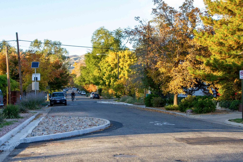 A photo of a curb extension that forms a chicane on the 800 East Neighborhood Byway. A cyclist rides past in the distance.