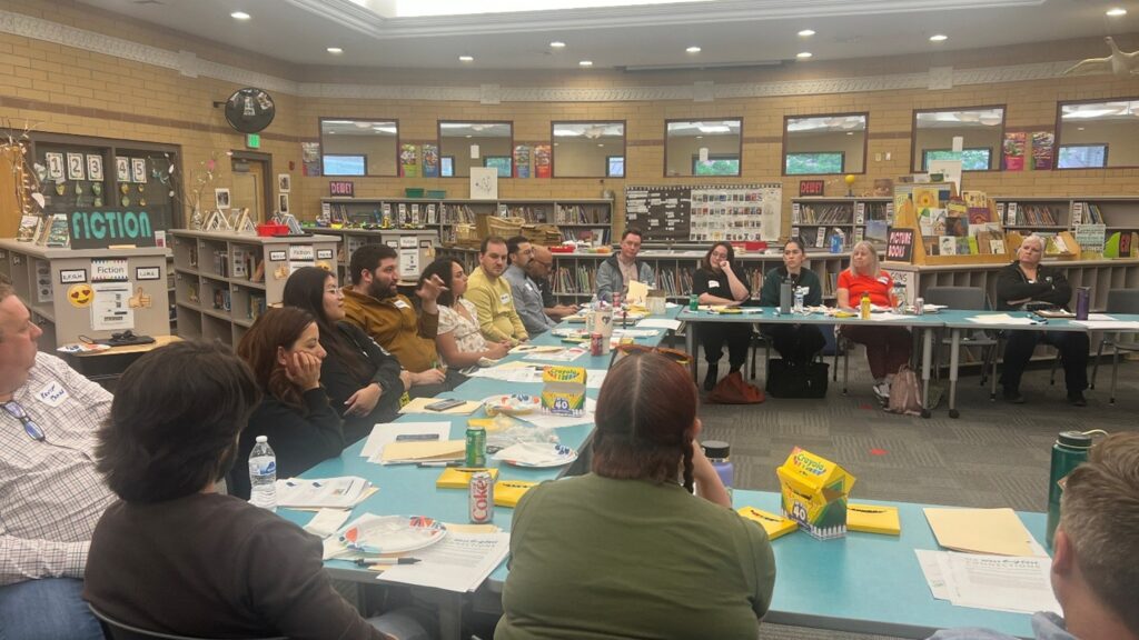 A photograph of a WE Connect Community Advisory Board meeting held inside a school library.