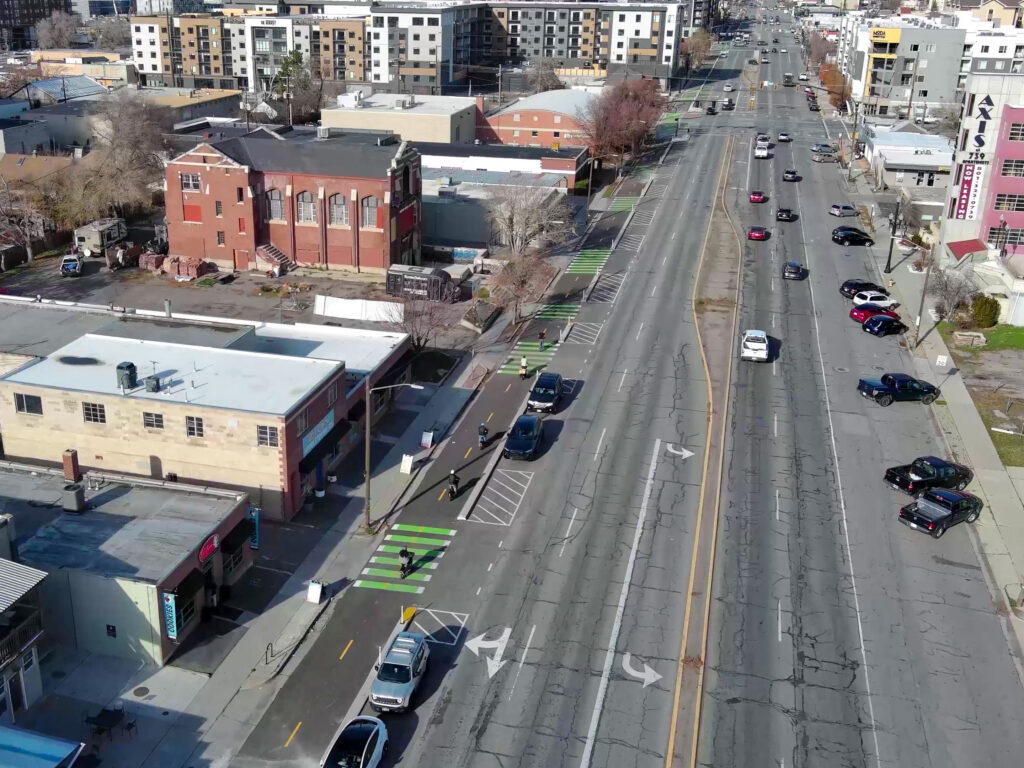 Aerial view of 300 West showing a two-way protected bike lane along the street, marked with green paint at crossings and separated from car traffic.